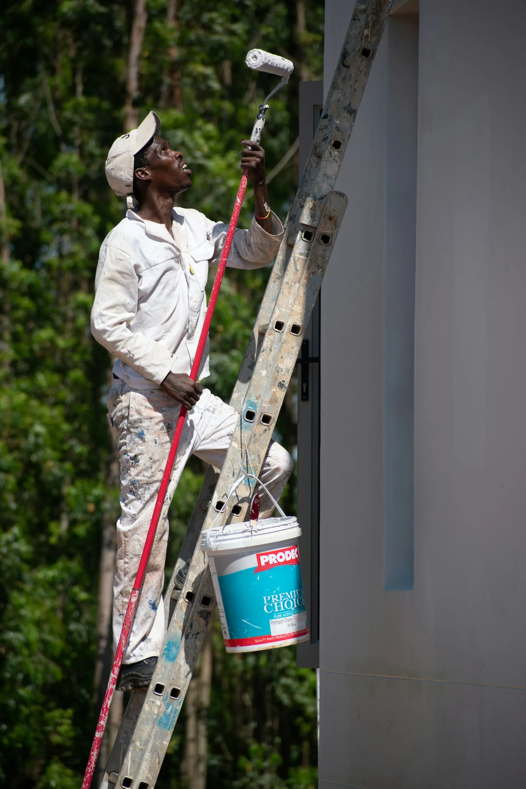 House painter on a ladder painting a home exterior